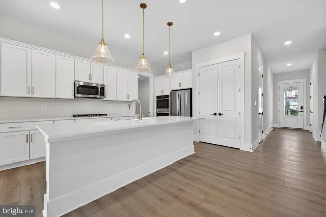 a view of kitchen with stainless steel appliances granite countertop a stove a sink a refrigerator and a wooden floor