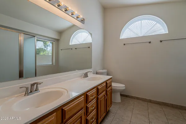 an empty room with wooden floor a ceiling fan and kitchen view