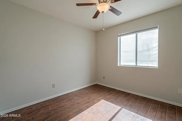 an empty room with wooden floor ceiling fan