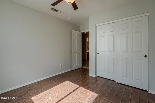 an empty room with wooden floor fan and windows