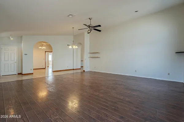 an empty room with wooden floor chandelier and windows