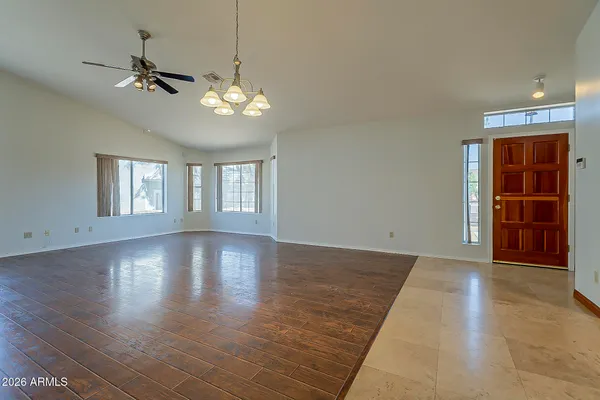 an empty room with wooden floor fan and windows