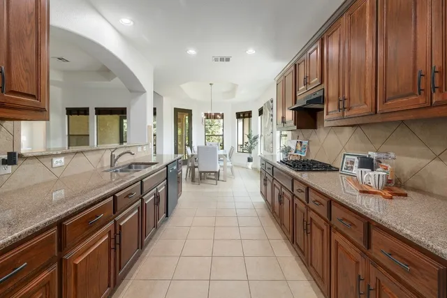 a large kitchen with stainless steel appliances granite countertop a sink stove and cabinets