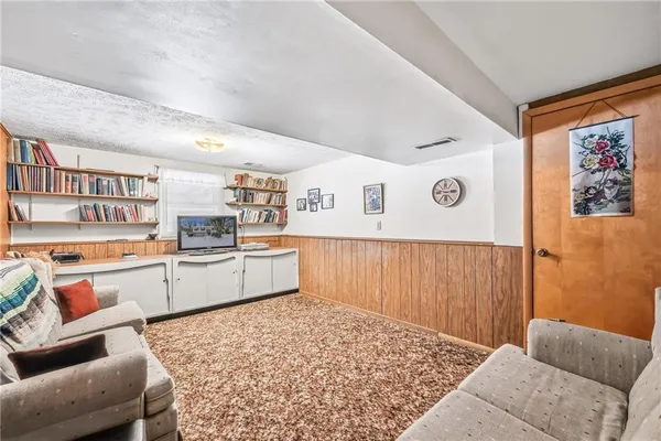 a living room with stainless steel appliances kitchen island granite countertop a couch and cabinets
