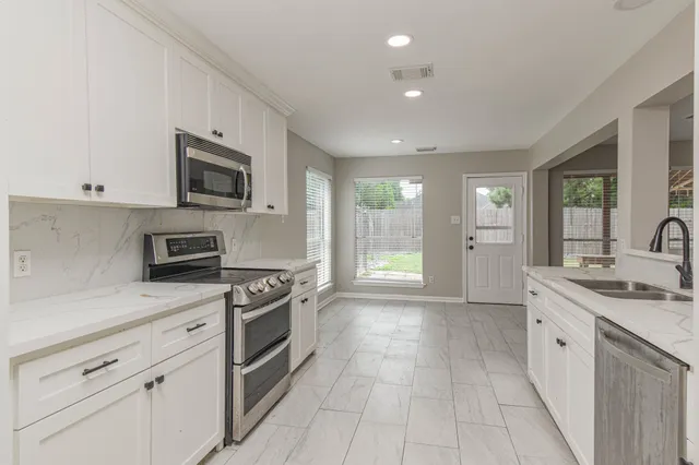 a kitchen with stainless steel appliances granite countertop a stove a sink and a microwave