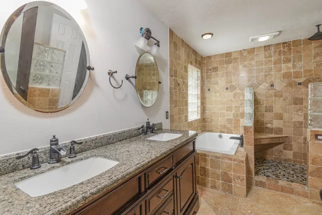 a bathroom with a granite countertop double vanity sink and a mirror