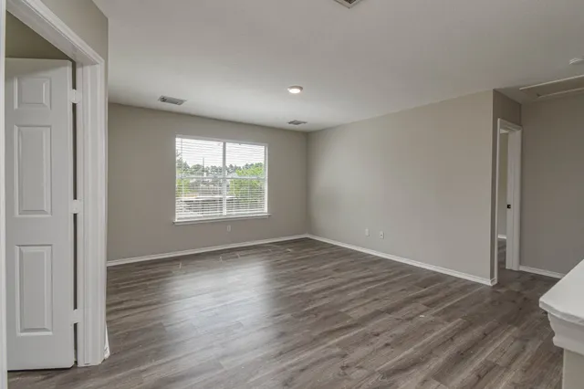 an empty room with wooden floor cabinet and windows
