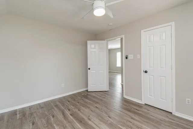a view of an empty room with wooden floor and a window