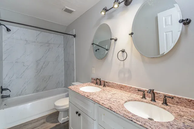 a bathroom with a granite countertop sink mirror toilet and bathtub