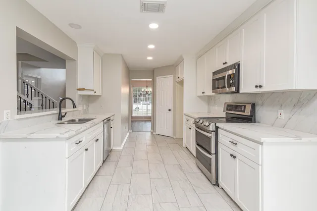 a kitchen with granite countertop white cabinets and white appliances