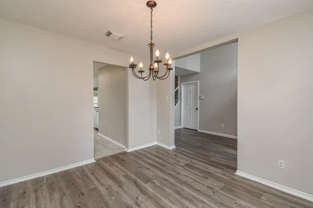 a view of a hallway with wooden floor and chandelier