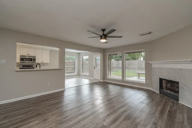 a view of an empty room with wooden floor and a window