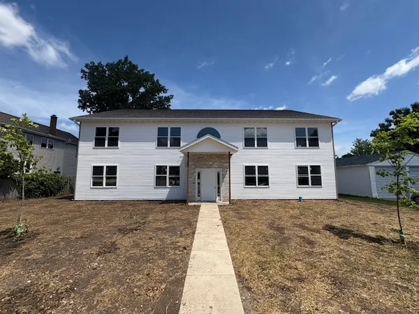 a front view of house with yard and trees in the background
