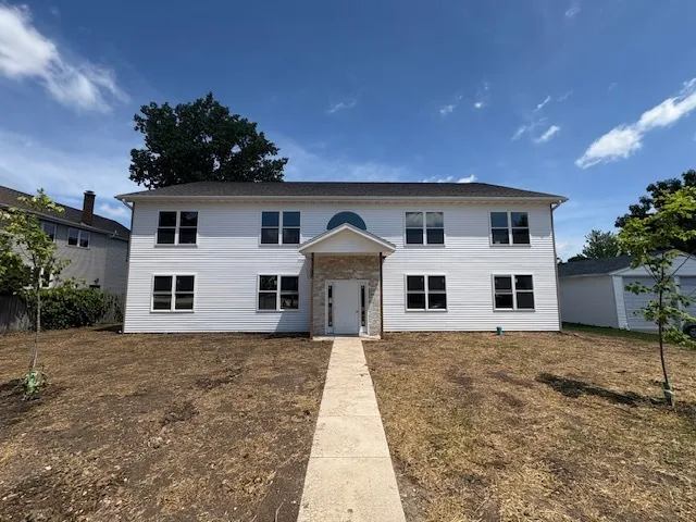 a front view of house with yard and trees in the background