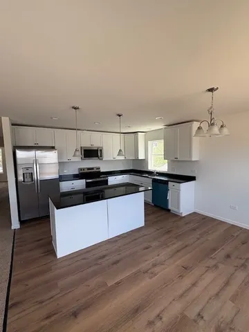 a large kitchen with kitchen island a sink dishwasher stove and oven with wooden floor