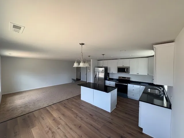 a kitchen with stainless steel appliances a sink a stove top oven a counter space and cabinets