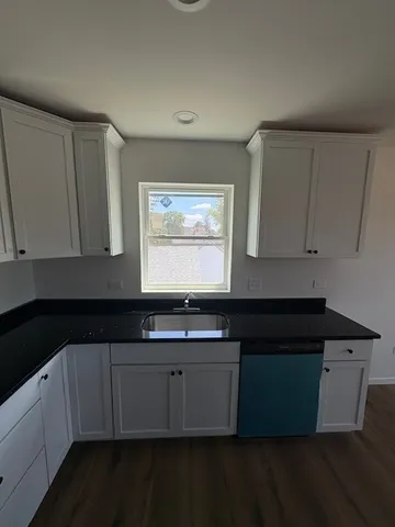 a kitchen with granite countertop white cabinets sink and window