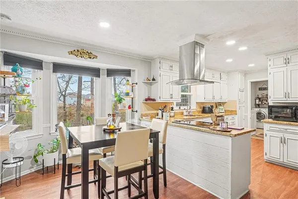 a kitchen with stainless steel appliances sink a stove and white cabinets with wooden floor