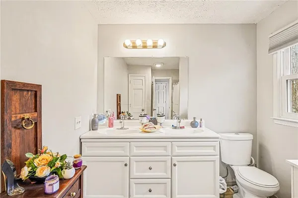 a bathroom with a granite countertop sink toilet and mirror