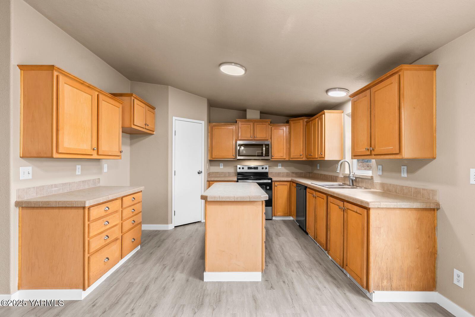 1023 Gibson Road Selah, WA 98942 - Photo 9 of 39 a kitchen with stainless steel appliances a stove top oven a sink a refrigerator a center island and a window
