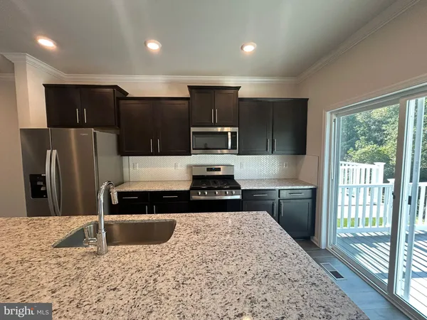 a kitchen with kitchen island granite countertop a refrigerator stove and sink