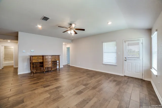 an empty room with wooden floor fireplace and windows