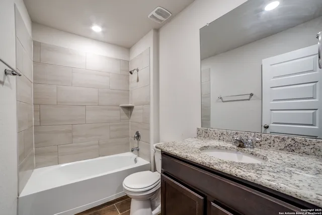 a bathroom with a granite countertop sink a toilet and bathtub