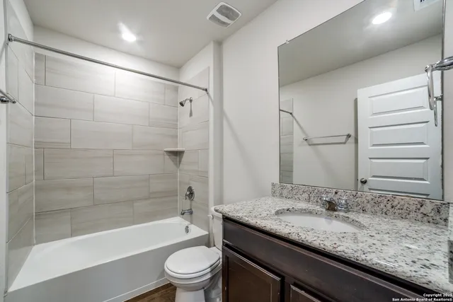 a bathroom with a granite countertop sink a toilet and bathtub