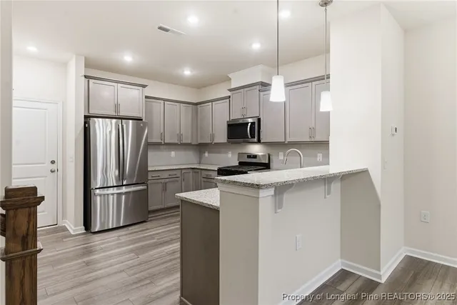 a kitchen with kitchen island a refrigerator sink and wooden floor