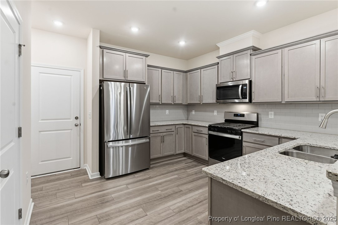 245 Ribbon Rail Street Fuquay-Varina, NC 27526 - Photo 15 of 43 a kitchen with granite countertop a refrigerator stove and microwave