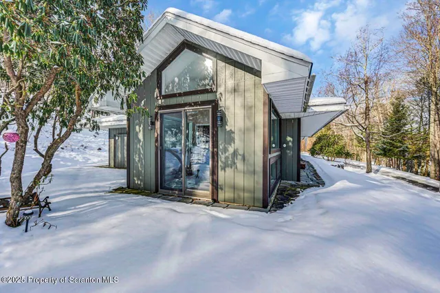 a front view of a house with a yard covered in snow