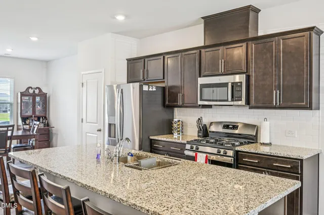 a kitchen with stainless steel appliances granite countertop a sink refrigerator and cabinets