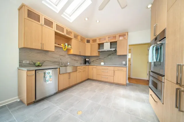 a kitchen with stainless steel appliances a sink a stove a refrigerator cabinets and a window