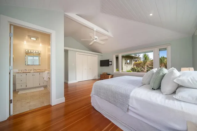 a bedroom with a large bed and wooden floor