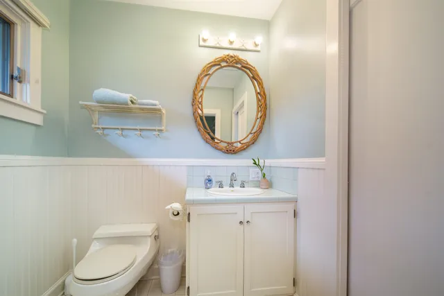 a bathroom with a toilet sink vanity and mirror