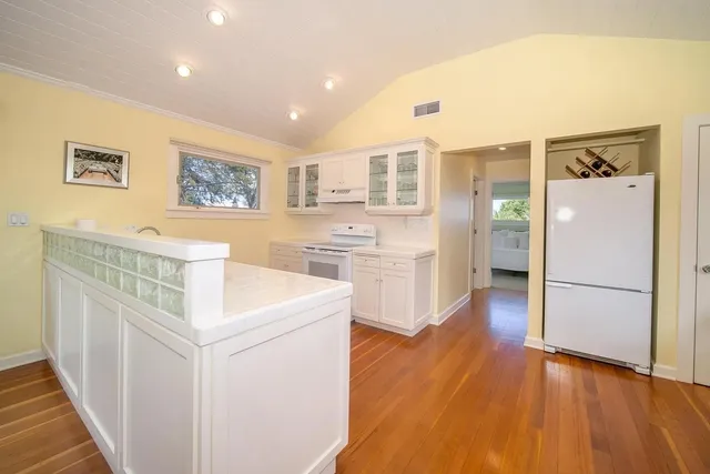 a open kitchen with stainless steel appliances granite countertop a refrigerator a stove and a wooden floors