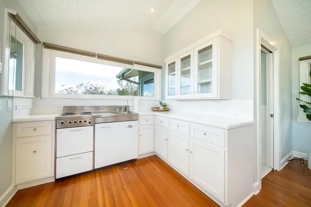 a kitchen with white cabinets and wooden floor