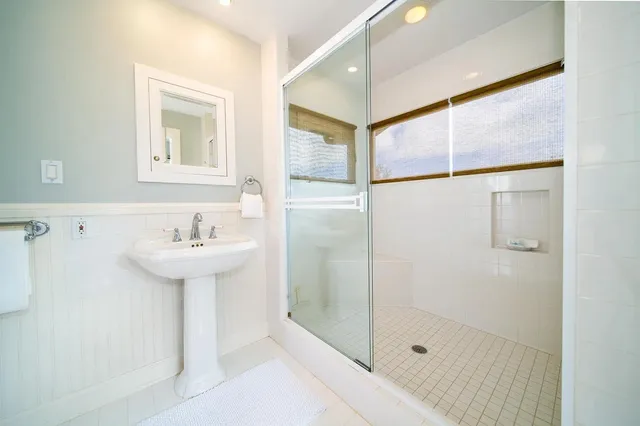 a bathroom with a sink shower and a mirror