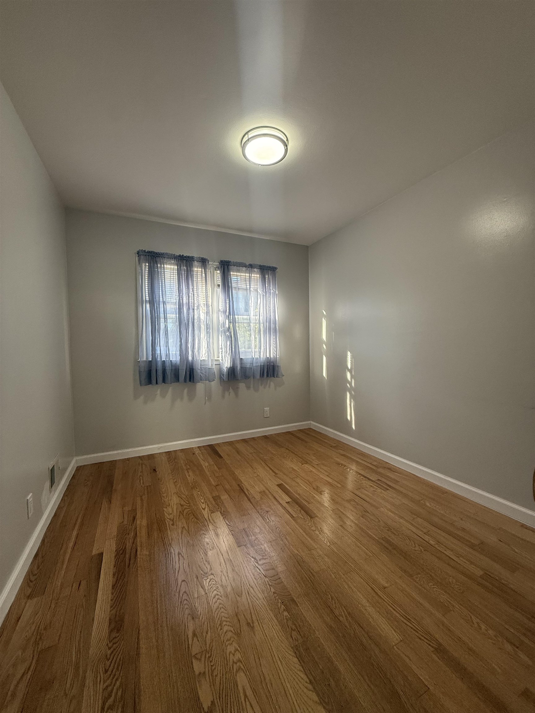 63 Prospect Avenue, Unit 2 Bayonne, NJ 07002 - Photo 11 of 14 an empty room with wooden floor and windows