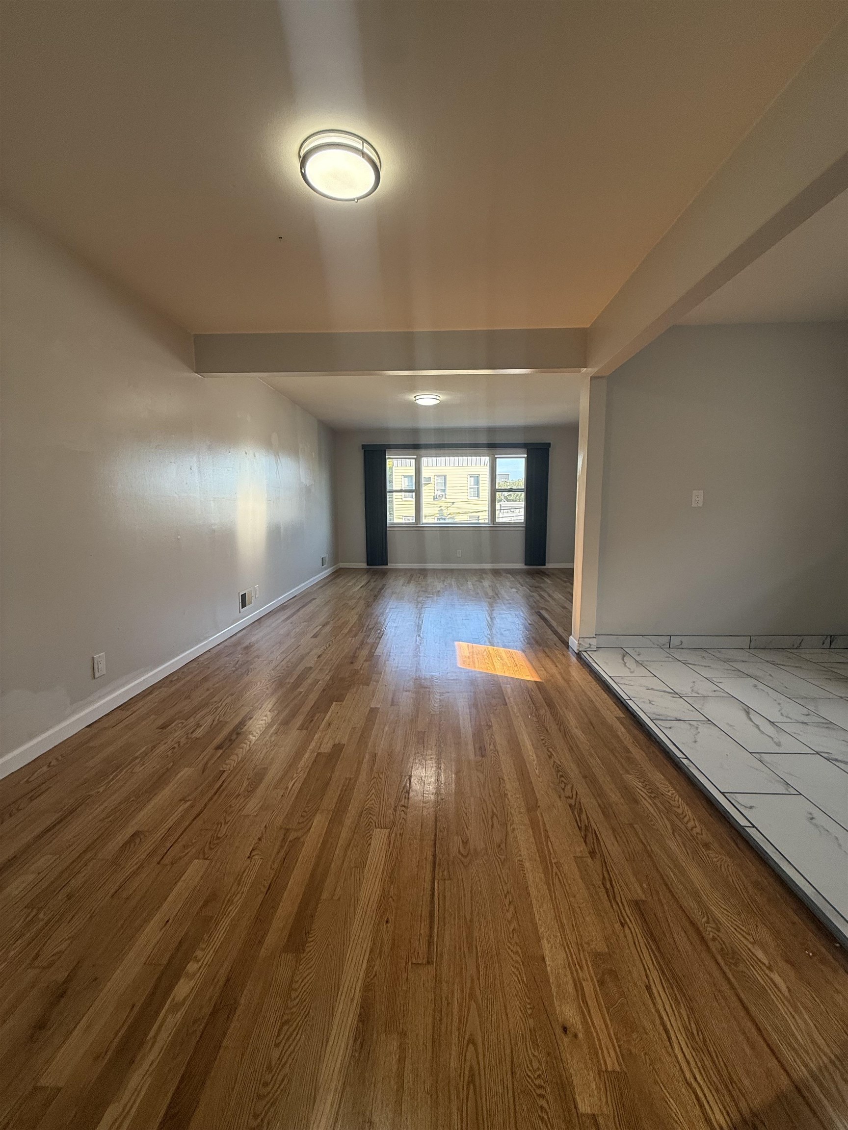 63 Prospect Avenue, Unit 2 Bayonne, NJ 07002 - Photo 2 of 14 an empty room with wooden floor and windows
