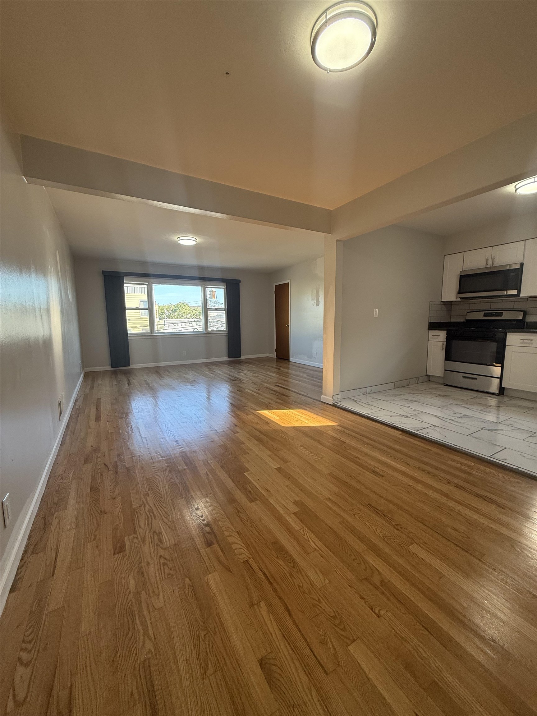 63 Prospect Avenue, Unit 2 Bayonne, NJ 07002 - Photo 3 of 14 wooden floor in an empty room with a window