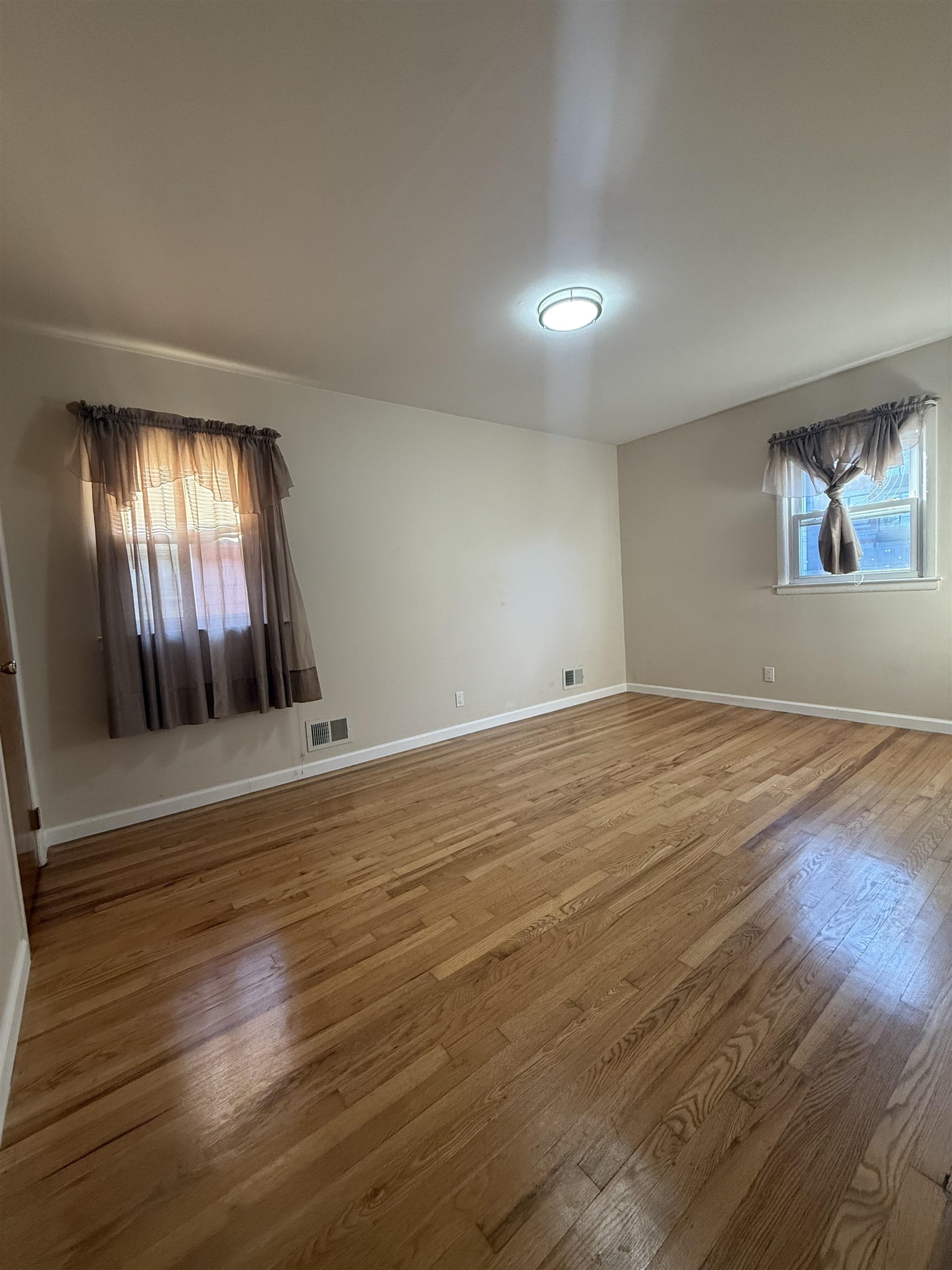 63 Prospect Avenue, Unit 2 Bayonne, NJ 07002 - Photo 9 of 14 an empty room with wooden floor and windows