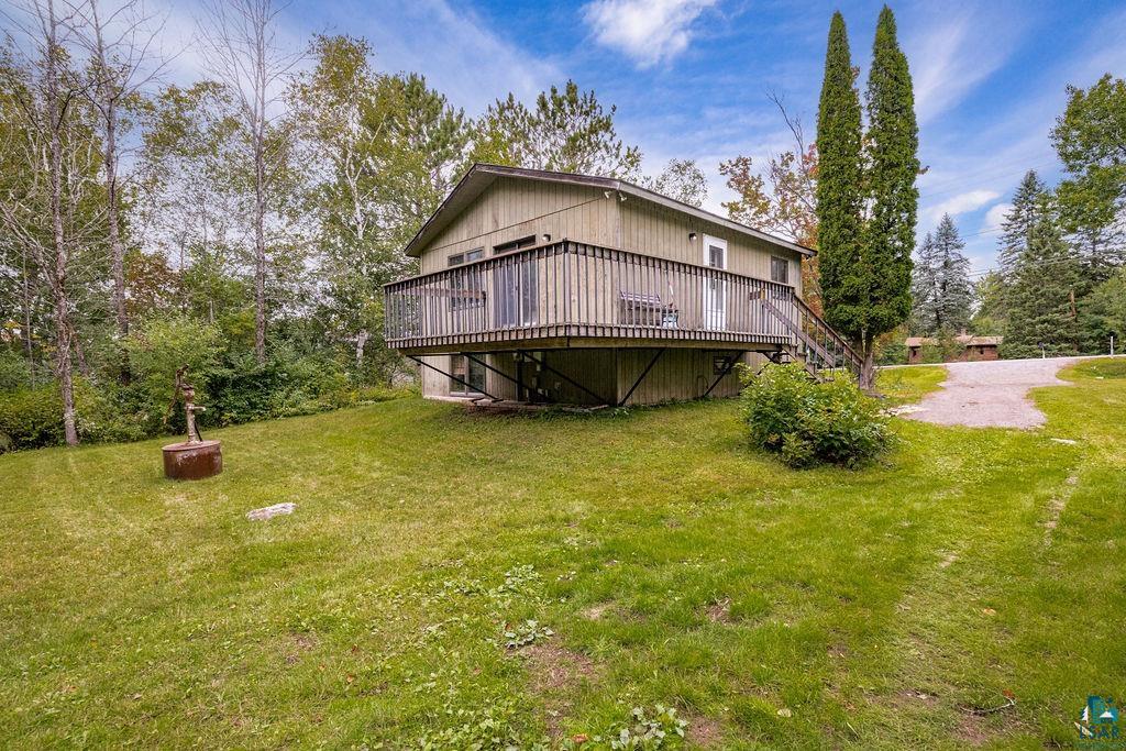 4738 Morris Thomas Road Hermantown, MN 55811 - Photo 2 of 19 Elevated deck with wood railing, siding exterior, mature trees, and a gravel driveway