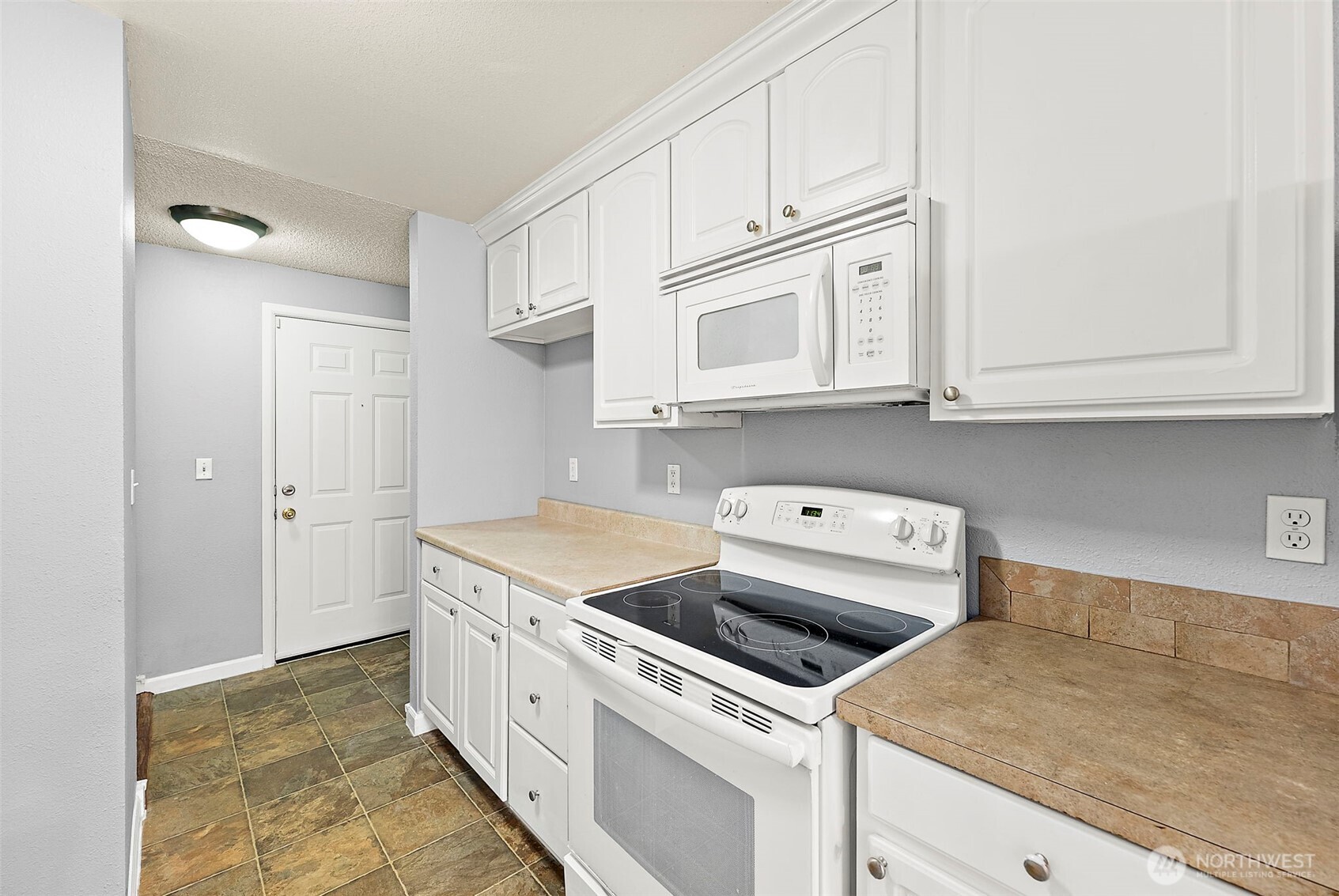 10010 Golden Given Road East, Unit 4 Tacoma, WA 98445 - Photo 3 of 19 a kitchen with stainless steel appliances granite countertop white cabinets and a stove