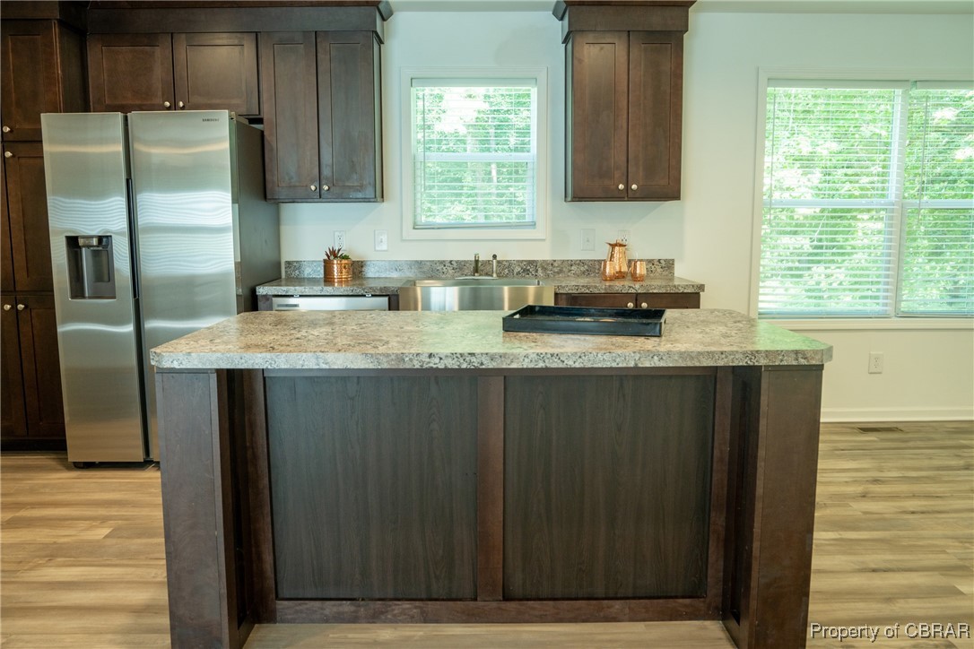 5726 Clay Bank Road Gloucester, VA 23061 - Photo 10 of 40 Kitchen featuring sink, light hardwood / wood-style flooring, dark brown cabinetry, and stainless steel fridge