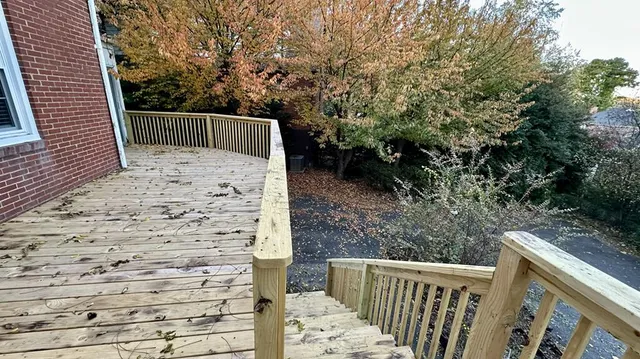 a view of a house with a large tree and wooden fence