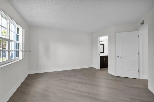 a view of empty room with wooden floor and windows