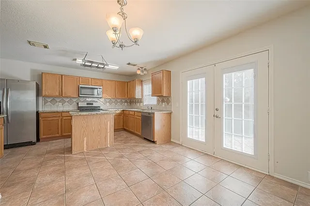 a large kitchen with granite countertop a stove a sink dishwasher a refrigerator and white cabinets with wooden floor