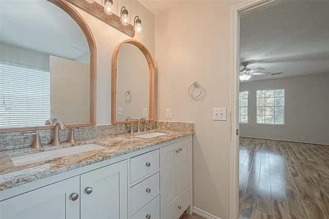 a bathroom with a granite countertop double vanity sink and mirror