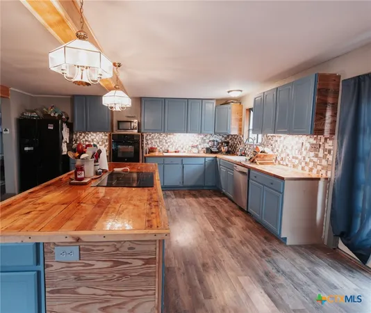 a kitchen with stainless steel appliances kitchen island granite countertop a refrigerator a sink dishwasher a stove with wooden cabinets and floor